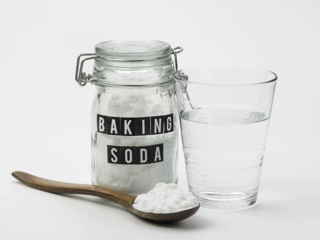 Pot of baking soda with spoon and glass of water