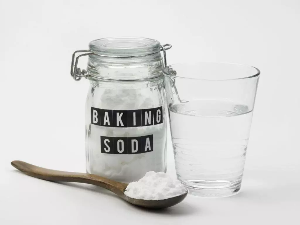 Pot of baking soda with spoon and glass of water